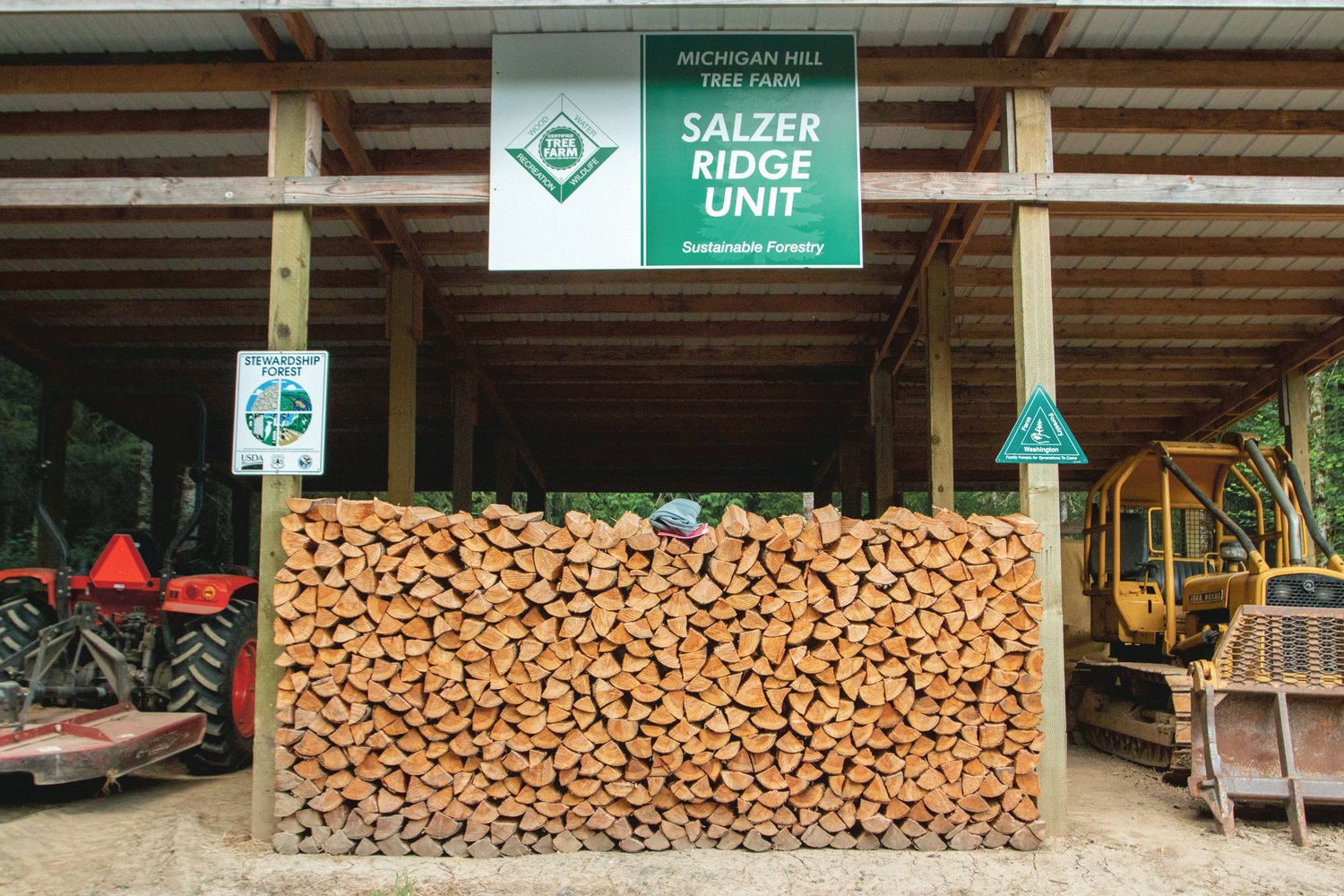 A stack of firewood sits underneath the Salzer Ridge Unit of Michigan Hill Tree Farm Sign